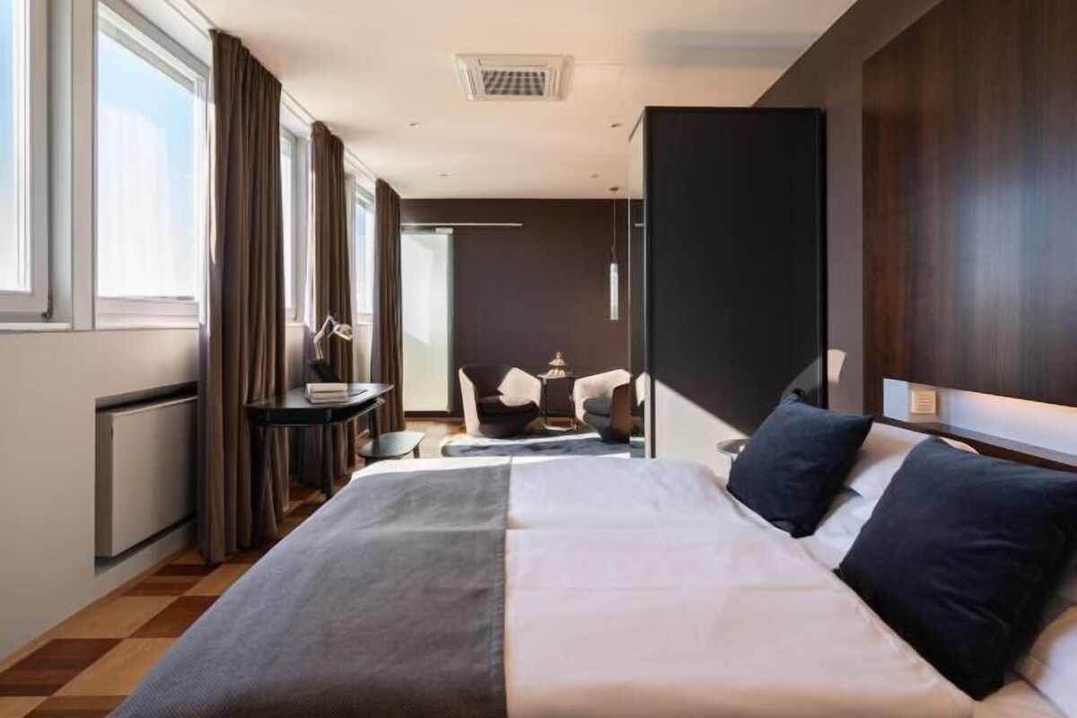A hotel room with a bed, a desk, and a chair.