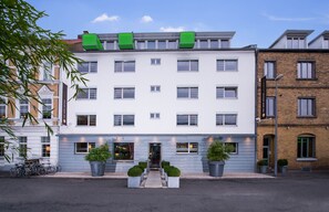 Welcome to our hotel, featuring a clean facade with a central doorway and potted plants.