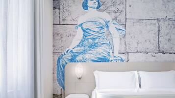 Una habitación de hotel con una cama, una lámpara de pared y un gran mural azul y blanco.
