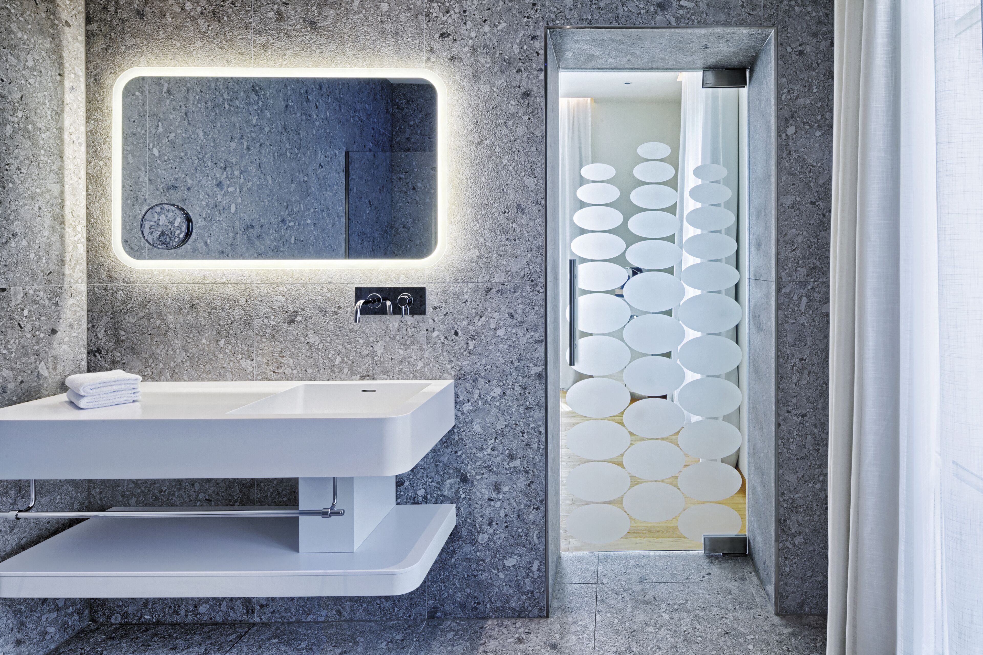 A modern bathroom with a rectangular mirror, a white sink, and a wall-mounted towel rack.