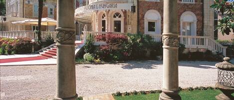 A hotel entrance with a stone archway, a paved pathway, and a well-maintained garden.