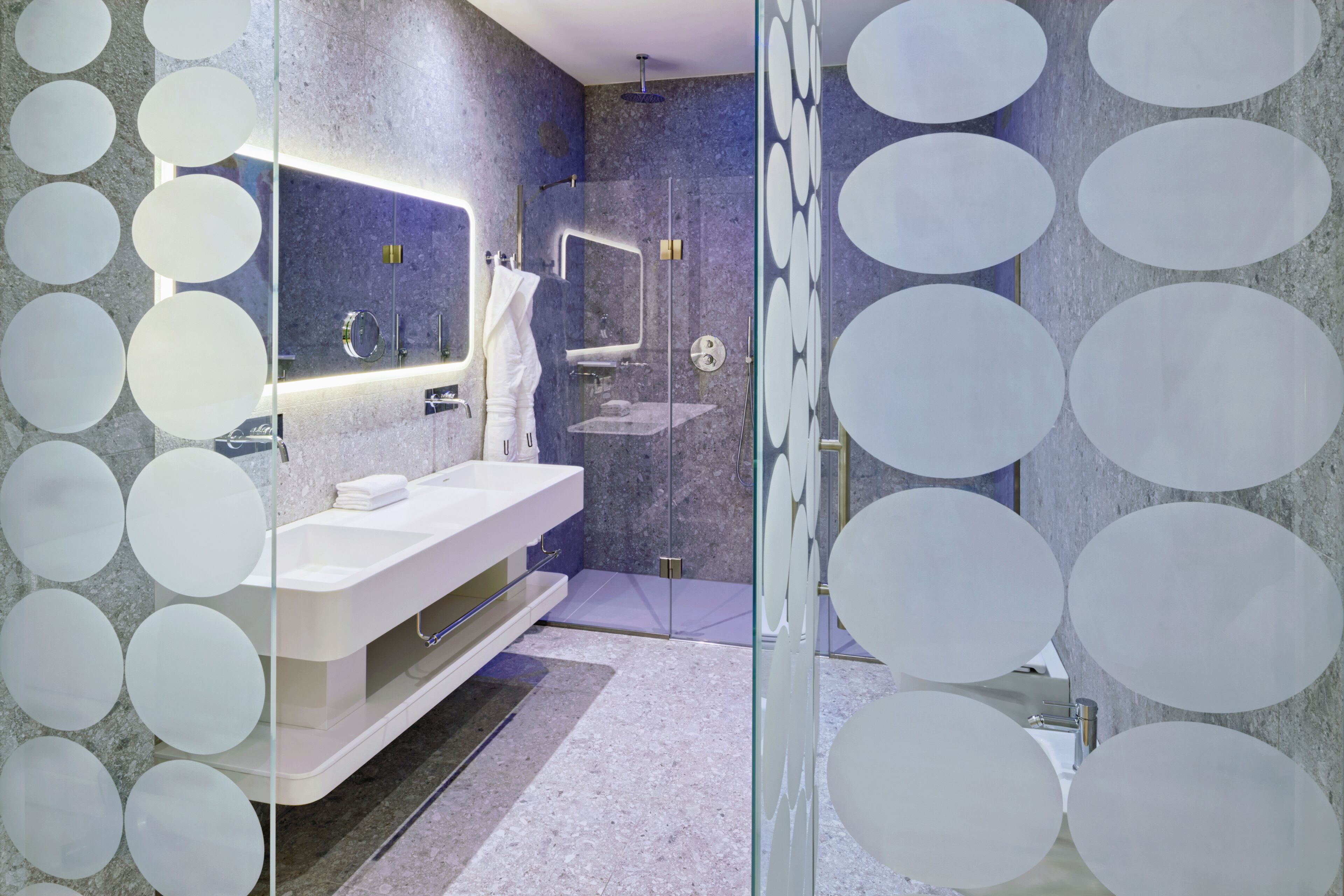 A modern bathroom with a glass shower enclosure, a white vanity, and a large mirror.