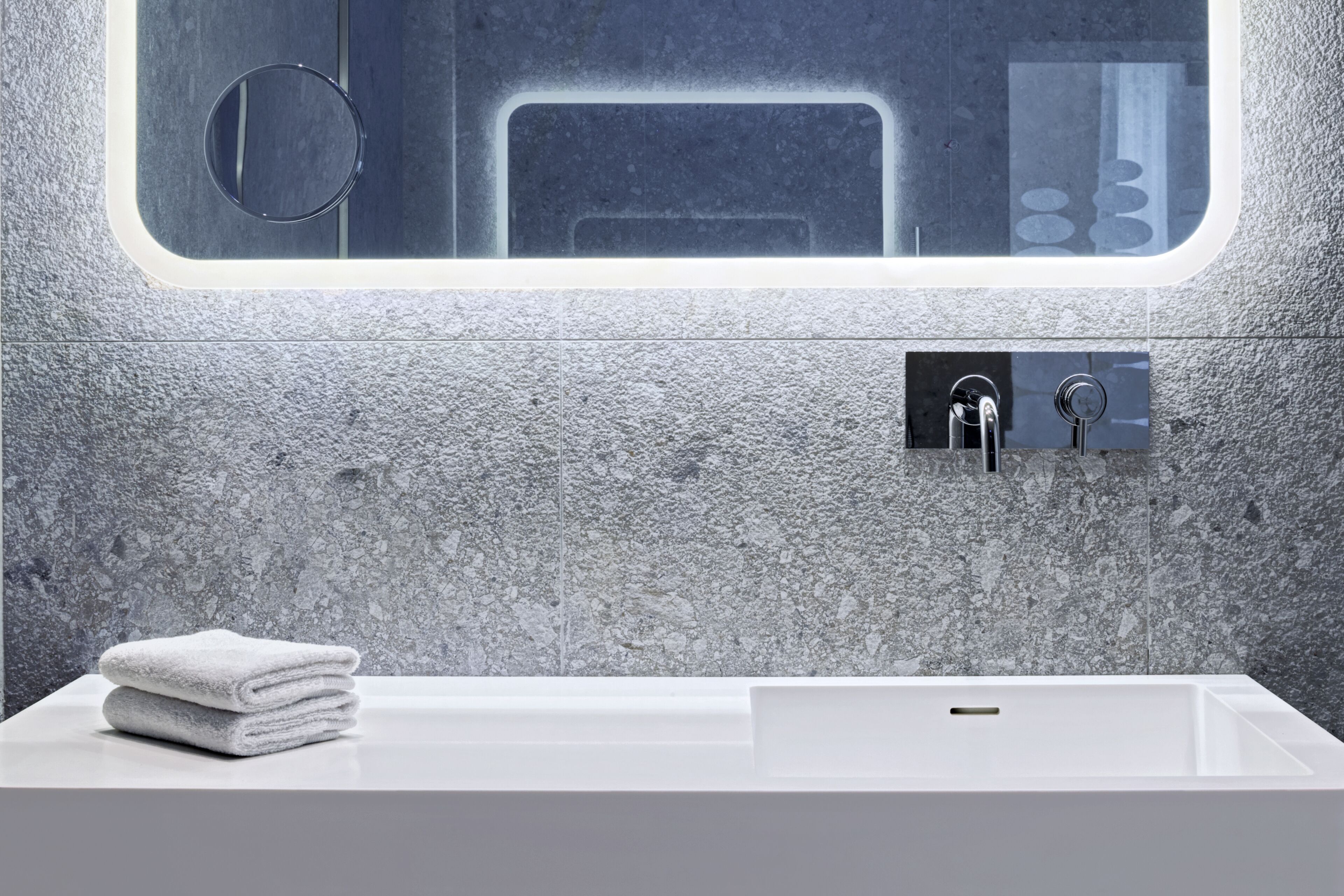 A bathroom with a white sink, a towel, and a mirror with a frosted glass window.