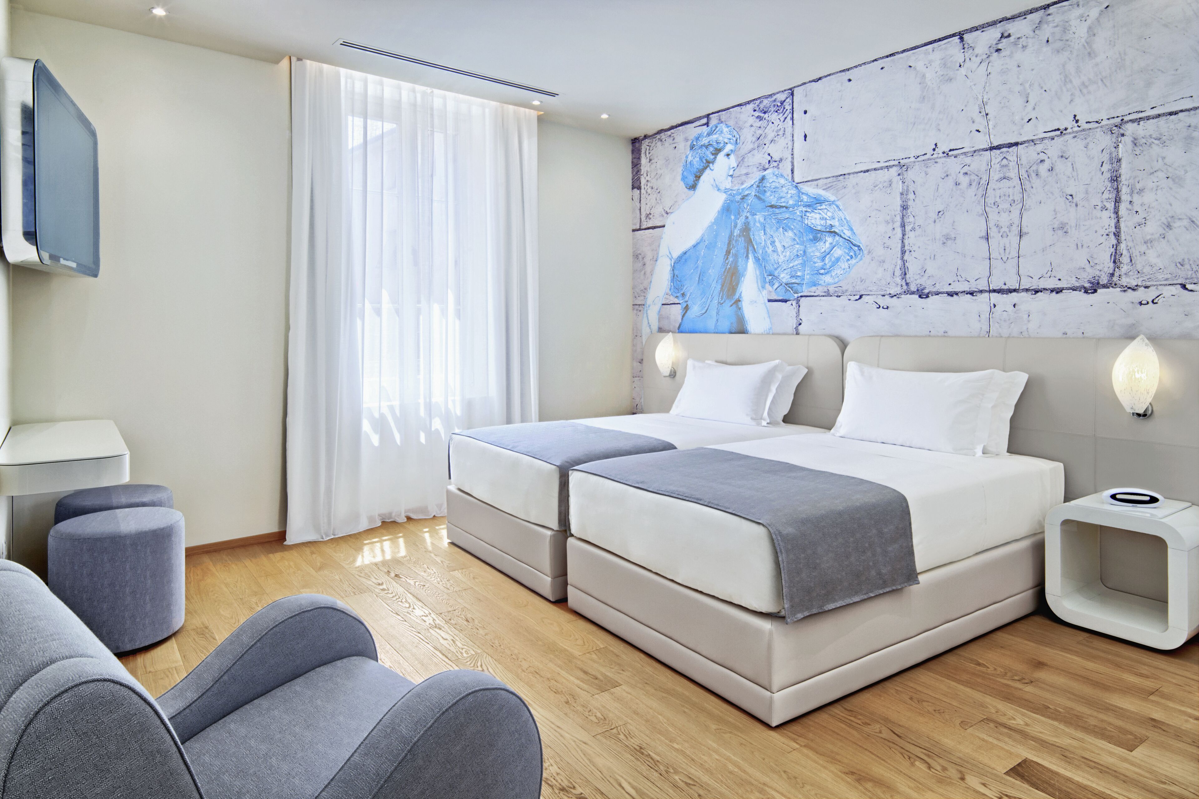 Una camera d'albergo moderna con un letto grande, una televisione a schermo piatto e un quadro appeso al muro.