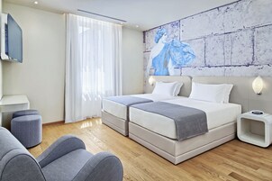 Una camera d'albergo moderna con un letto grande, una televisione a schermo piatto e un quadro appeso al muro.