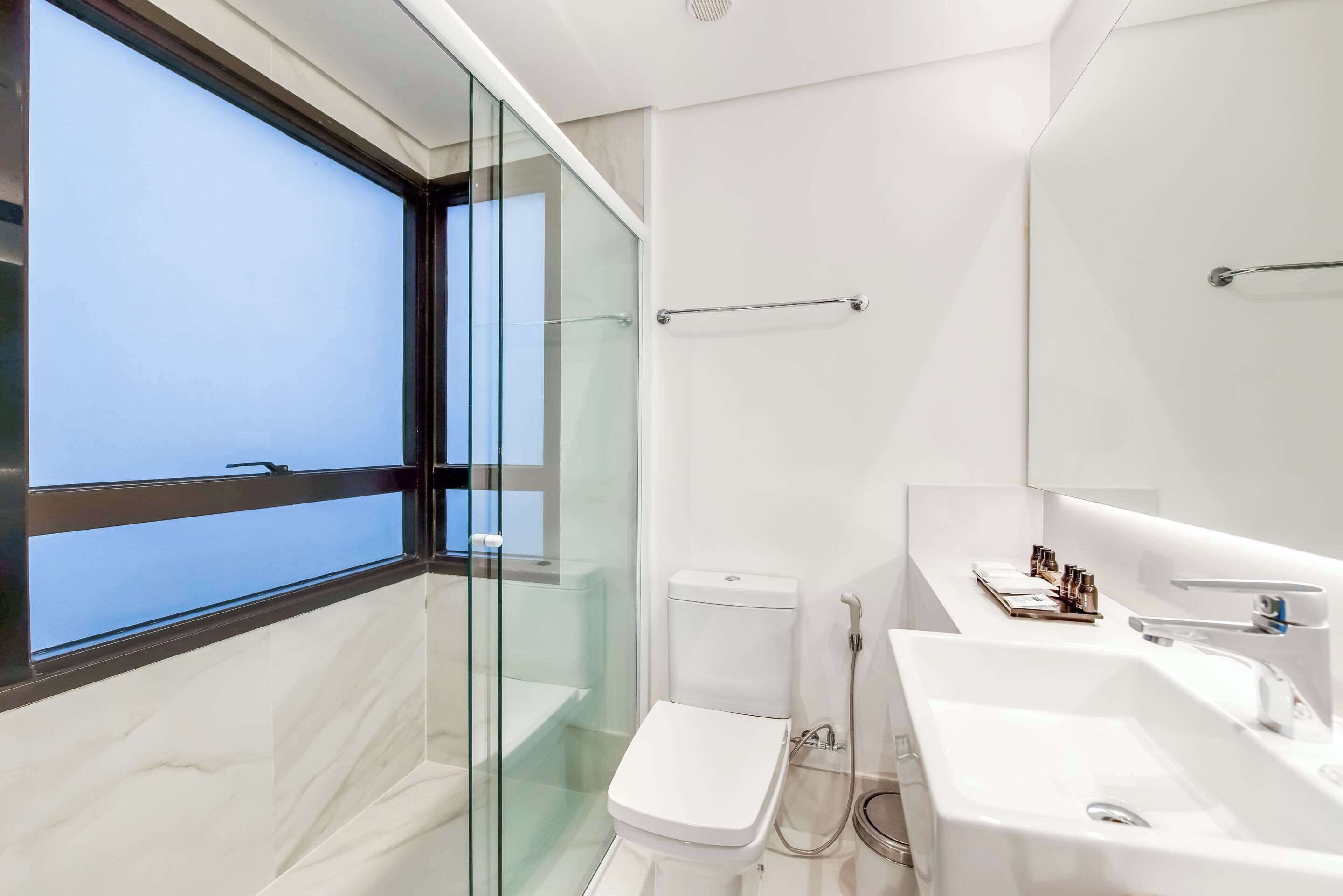 Ein modernes Badezimmer mit Duschkabine aus Glas, Toilette und Waschbecken mit Spiegel.