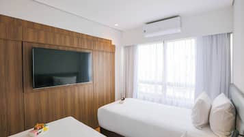 Quarto de hotel com duas camas, uma televisão fixada na parede e um ar condicionado.