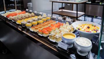 Un buffet con diverse pietanze, tra cui pasticcini, frutta e dolci.