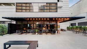 Un espace extérieur aménagé avec du mobilier moderne et une partie couverte décorée de guirlandes lumineuses.