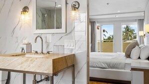 A modern bathroom with a marble sink, a large mirror, and two wall sconces. - Hotel Ocean (Miami Beach)