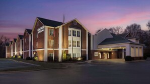A multi-story hotel with a brick facade, large windows, and a well-lit entrance.