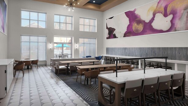 A modern dining area with hexagonal patterned flooring, multiple tables and chairs, and large windows allowing natural light.