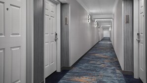 A hotel hallway with white doors, a patterned carpet, and a long corridor. - Homewood Suites by Hilton Ft. Worth-North at Fossil Creek (Fort Worth)