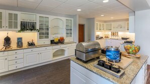 A modern kitchen with white cabinets, a built-in waffle maker, a coffee machine, and a large Oatmeal container. - Homewood Suites by Hilton Ft. Worth-North at Fossil Creek (Fort Worth)