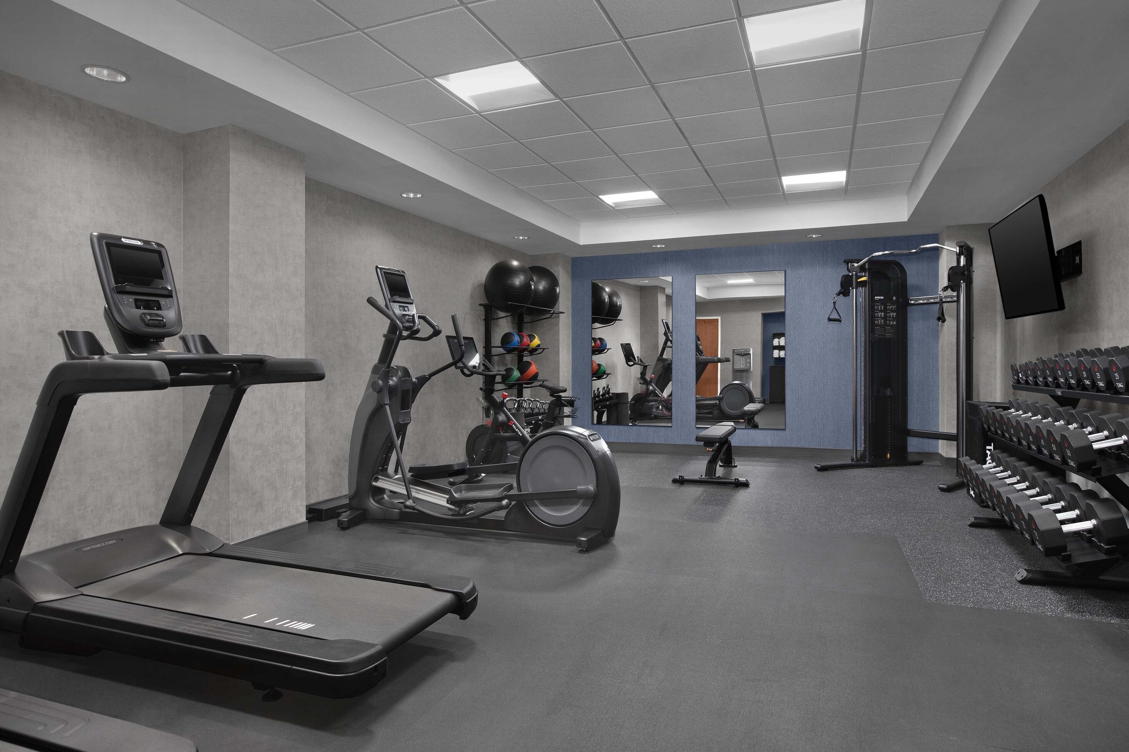 Een fitnessruimte met loopbanden, elliptische trainers, een roeimachine en gewichthefapparatuur.