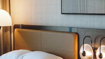 A hotel room with a bed, a bedside table with a lamp, a phone, and a wall-mounted light fixture.