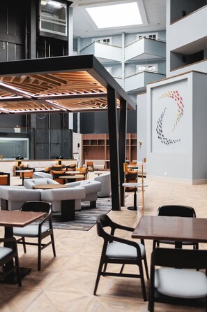 A modern interior with seating areas, a staircase, and a wall with a geometric art piece.