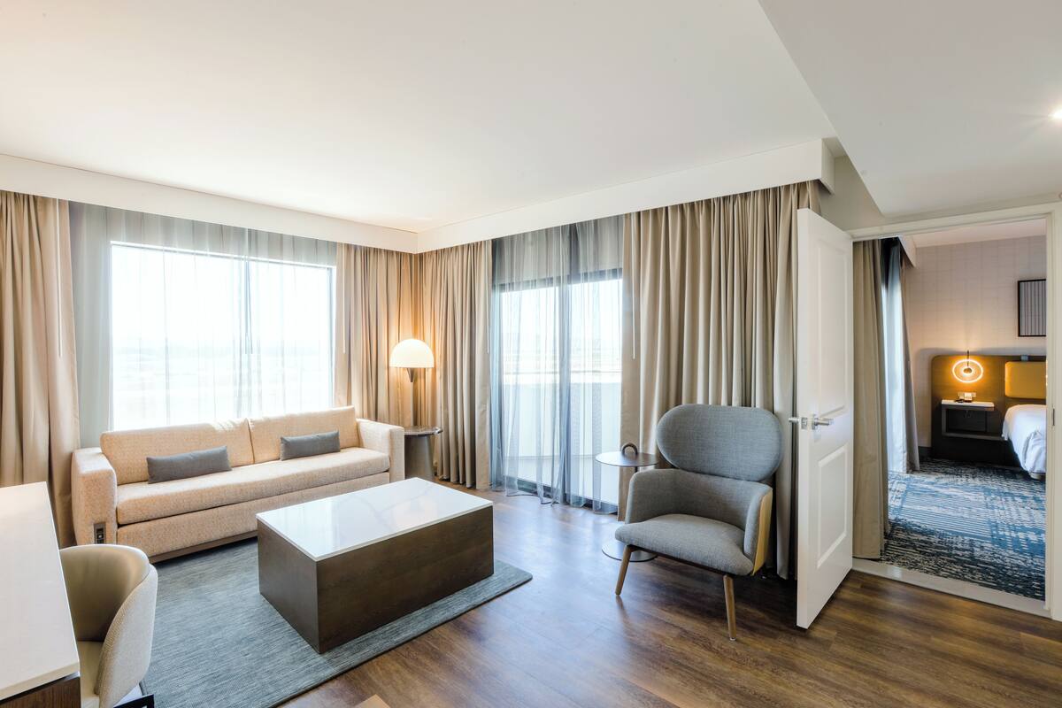 A hotel room with a sofa, armchair, and a small table.