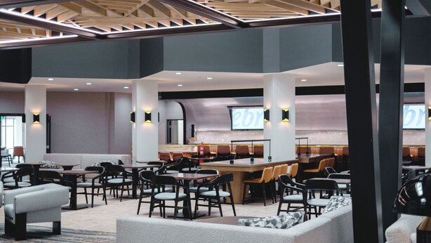 A spacious lobby with a high ceiling, multiple seating areas, and a central bar.
