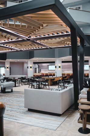 A spacious lobby with a high ceiling, multiple seating areas, and a central bar.