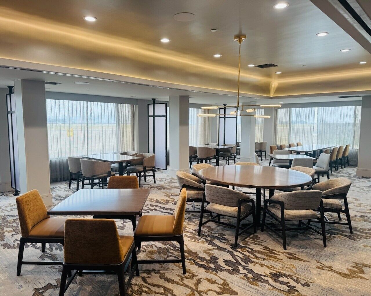 Uma sala de conferências de hotel com mesas redondas, cadeiras e piso coberto de carpete.