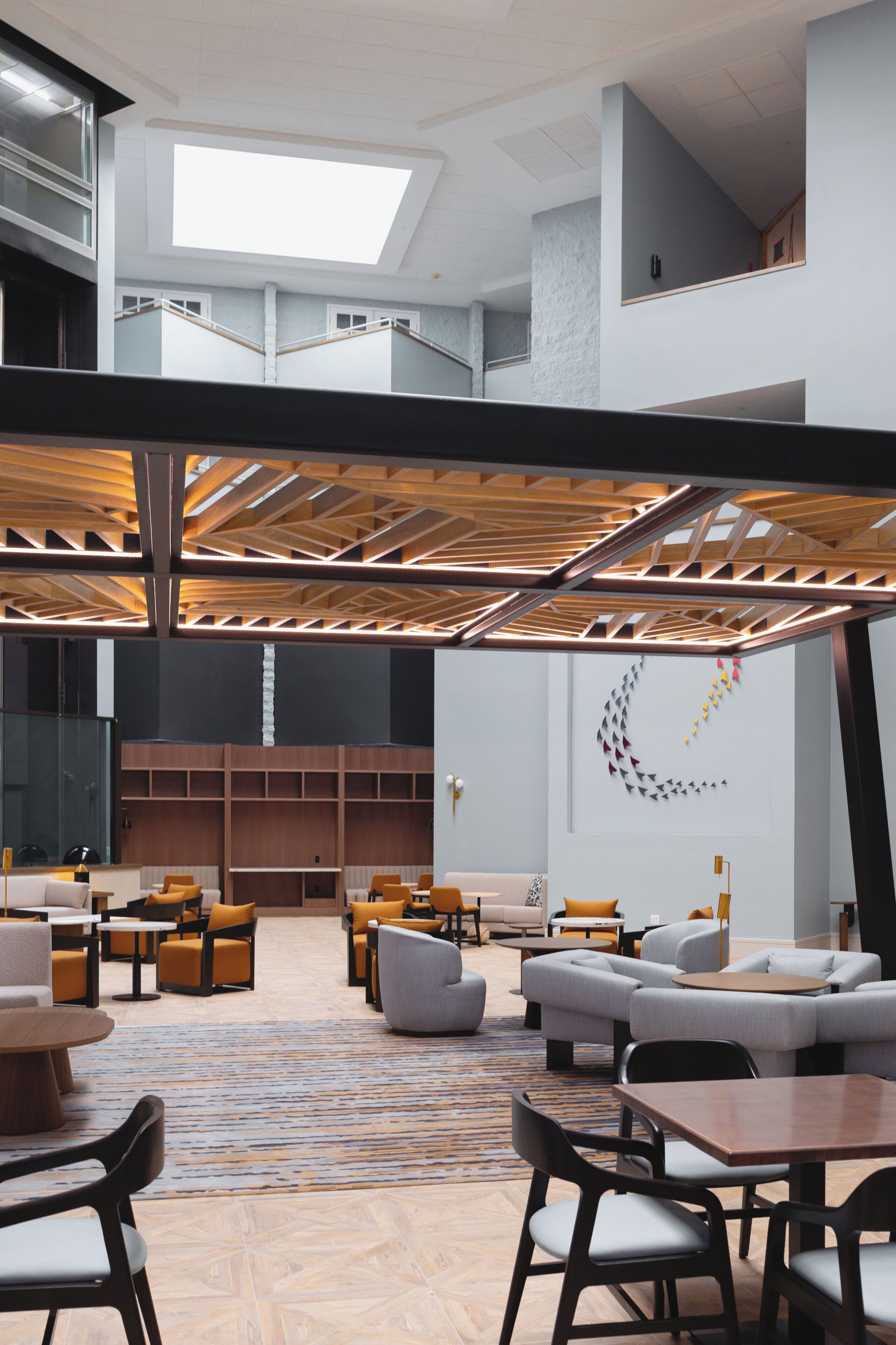 A spacious lobby with seating areas, a staircase, and a modern ceiling design.