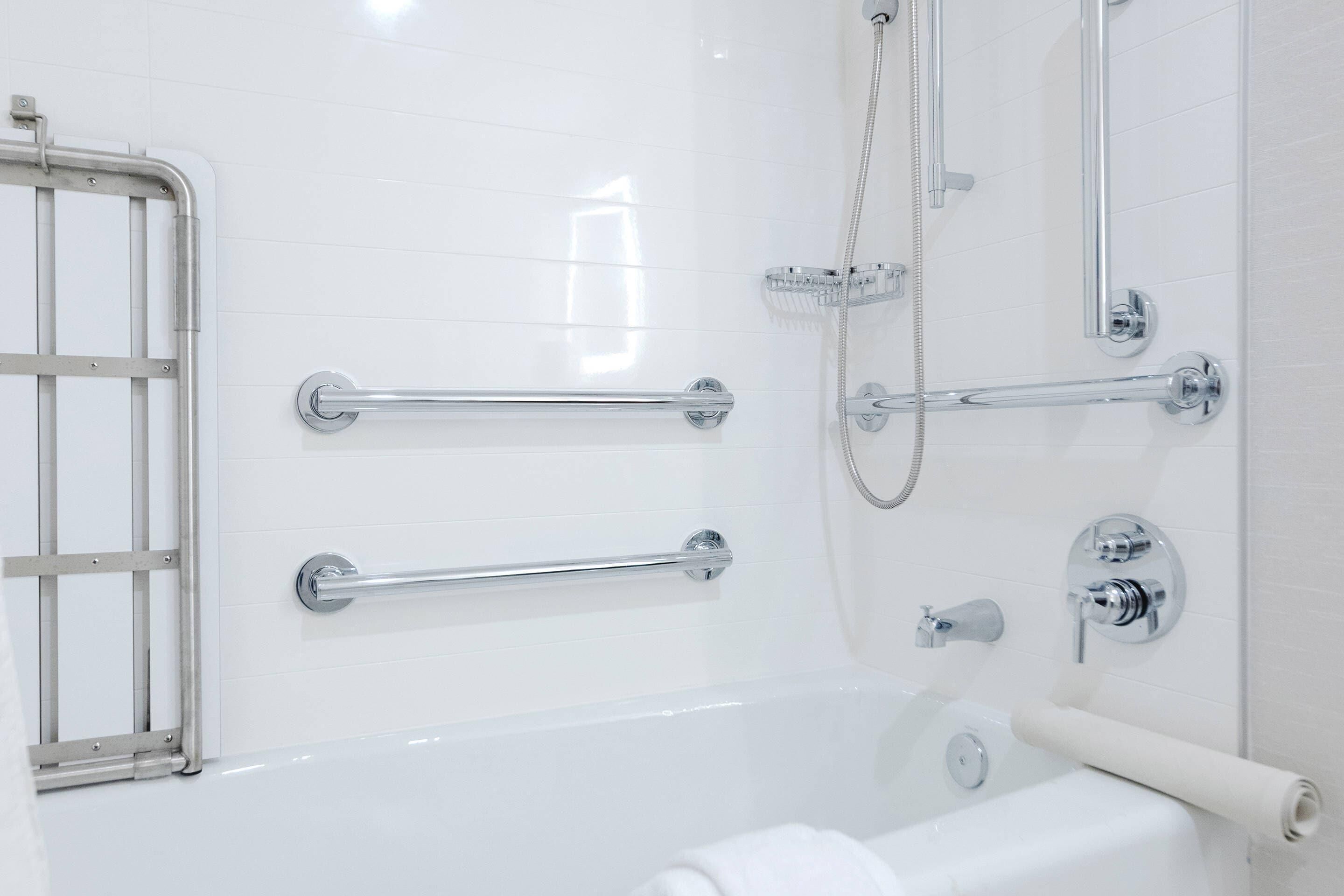 Un baño moderno con bañera, ducha y barras de apoyo para accesibilidad.