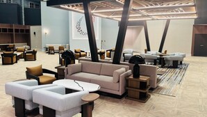 A spacious lobby with multiple seating areas, a high ceiling with exposed beams, and a modern design.