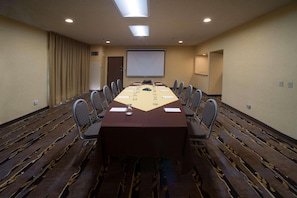 Conference room with a long table and chairs, carpeted floor, projector, and door.