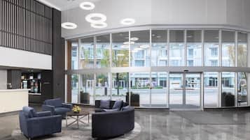 A lobby with seating, a reception desk, and large windows.