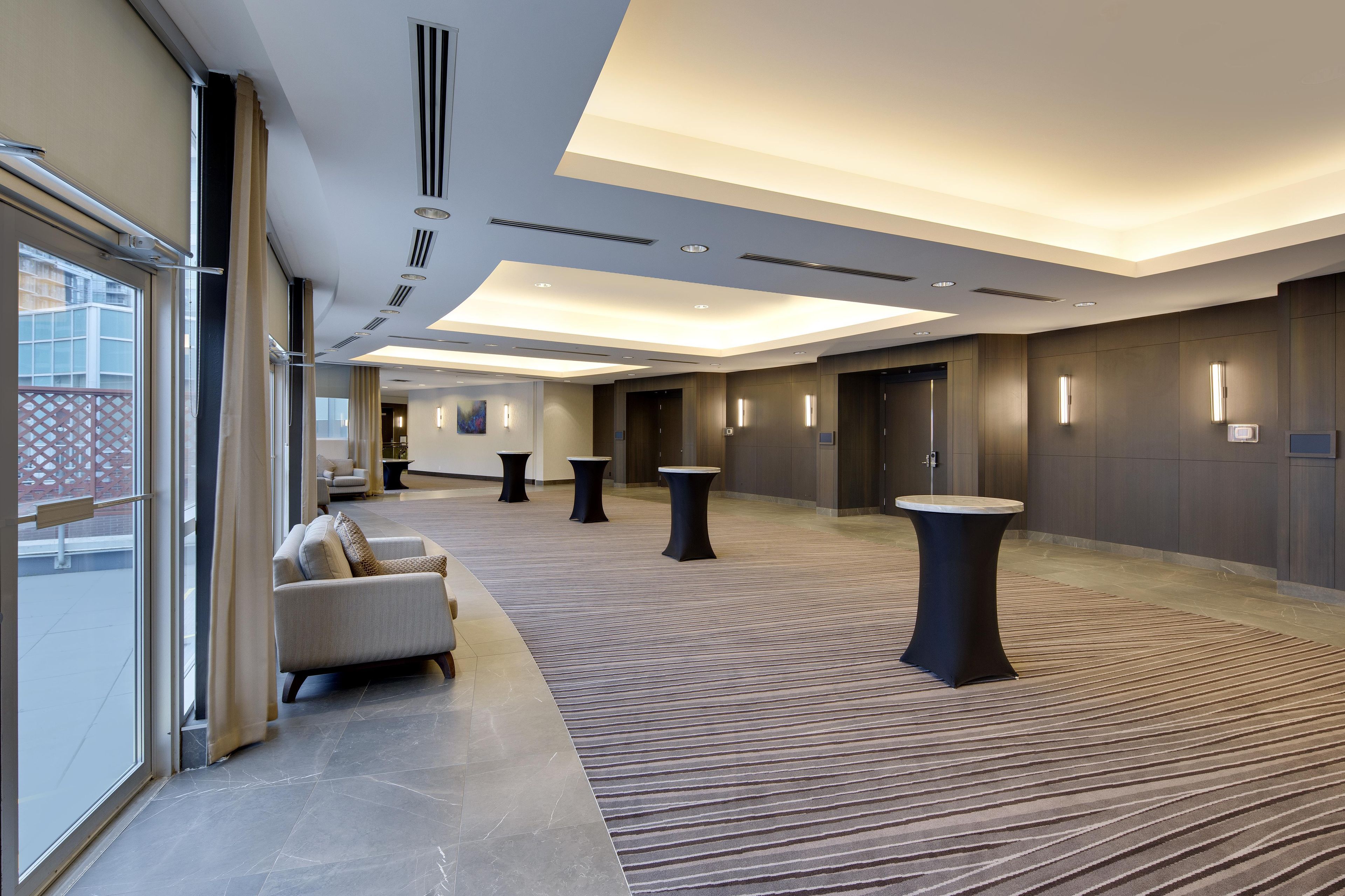A spacious hotel lobby with a sofa, tables, and a patterned carpet.