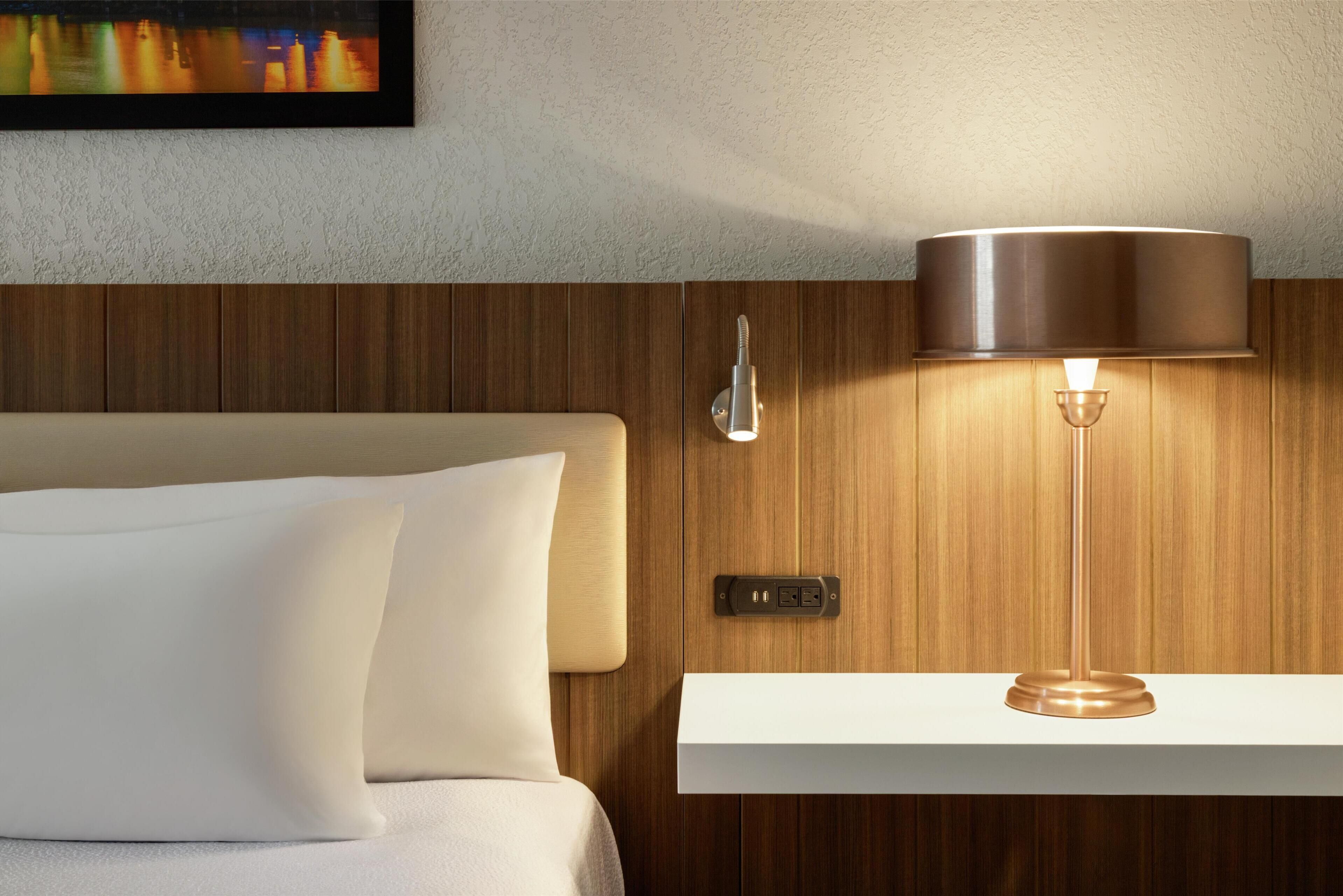 Une chambre d’hôtel avec un lit, une lampe fixée au mur et un décor mural en panneaux de bois.