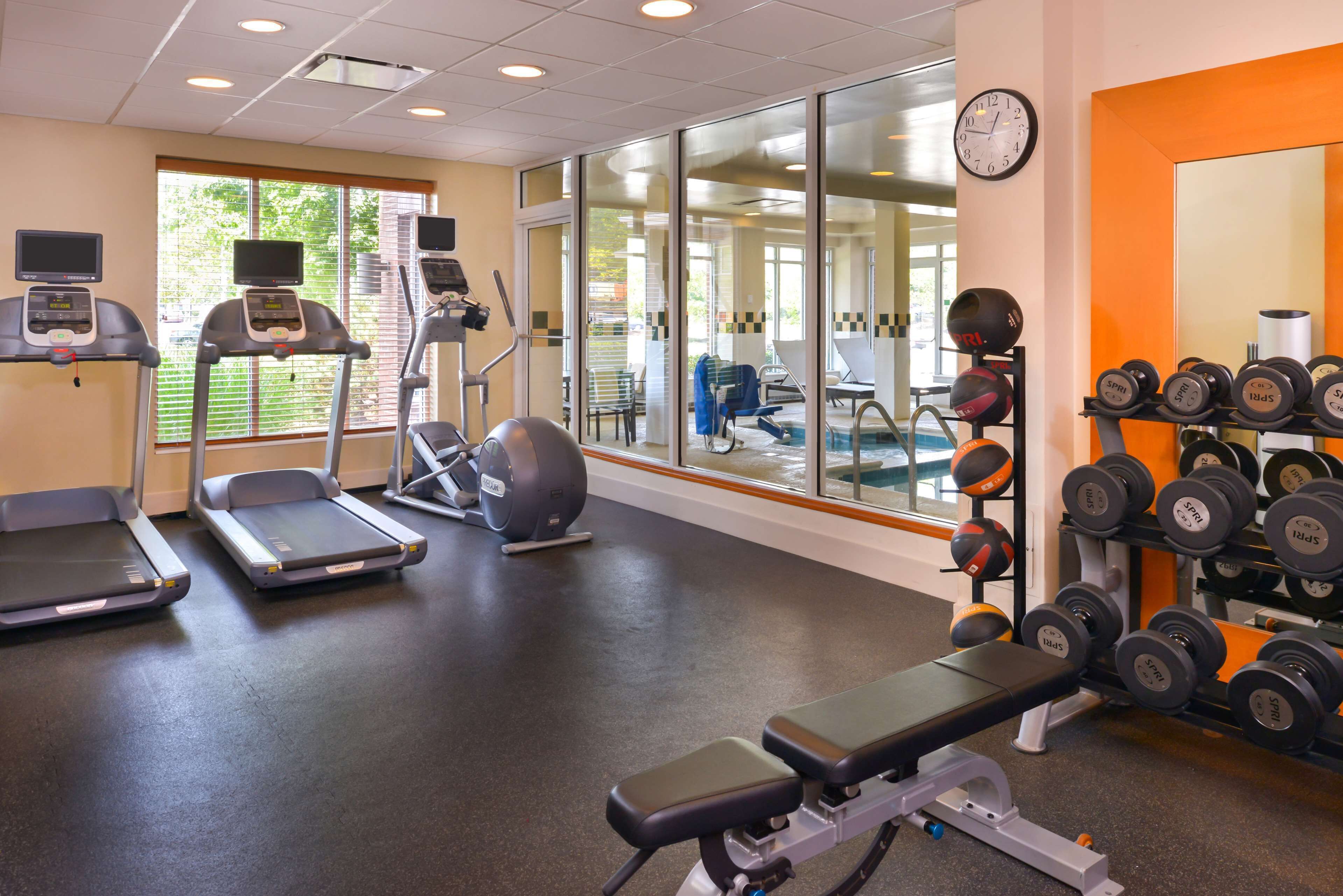 Une salle de sport équipée de tapis de course, d’un vélo d’appartement, d’un banc de musculation et d’une série d’haltères.