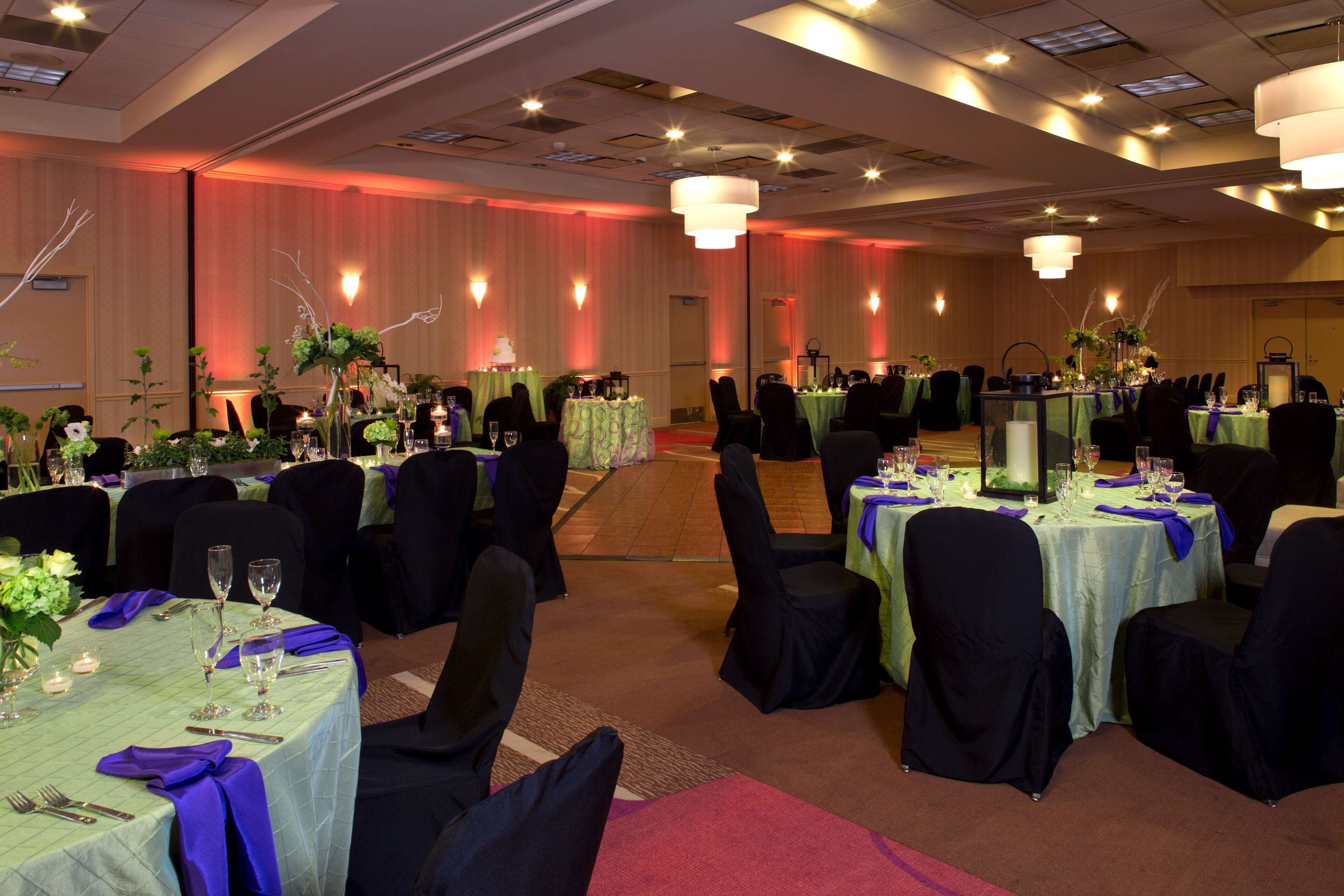 Un salón de banquetes con varias mesas redondas, cada una dispuesta con sillas y preparación para los comensales.
