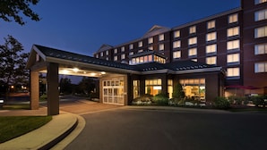 En hotellentrén med en överbyggd gång, en fasad av tegel och flera fönster.