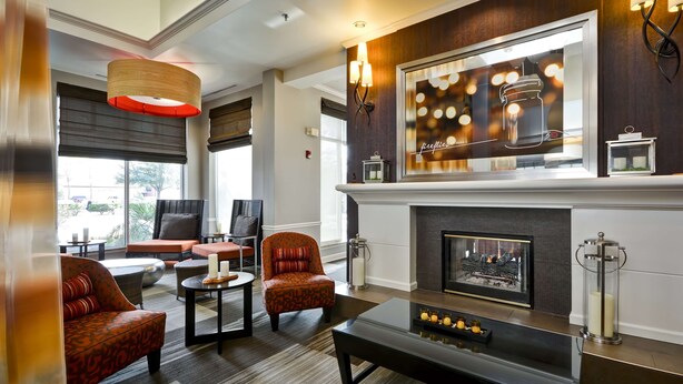 A modern lobby with a fireplace, comfortable seating, and a large window offering a view of the outdoors. - Hilton Garden Inn Austin/Round Rock (Round Rock)