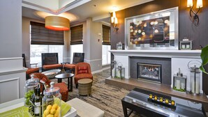 A modern hotel lobby with a fireplace, seating area, and a bar with candles. - Hilton Garden Inn Austin/Round Rock (Round Rock)