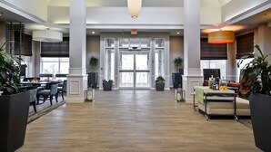 A spacious lobby with a wooden floor, large pendant lights, and potted plants. - Hilton Garden Inn Austin/Round Rock (Round Rock)