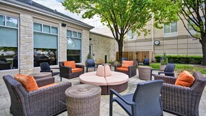 An outdoor patio area with wicker furniture, including sofas and chairs, and a round coffee table. - Hilton Garden Inn Austin/Round Rock (Round Rock)