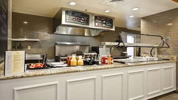 A buffet counter with a menu board, food items, condiments, and a beverage station.