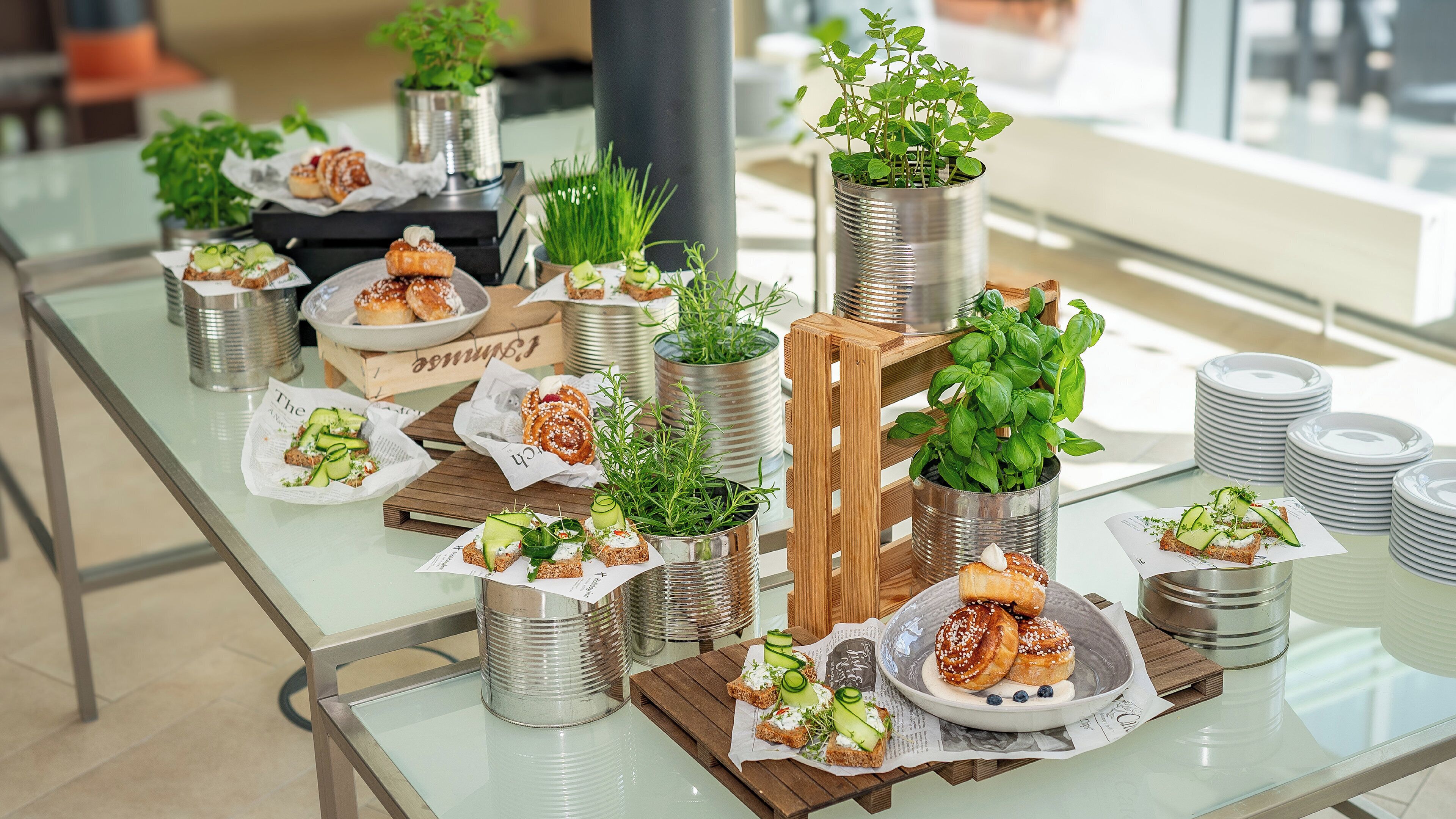 A buffet table with various food items and decorative plants in metal containers.