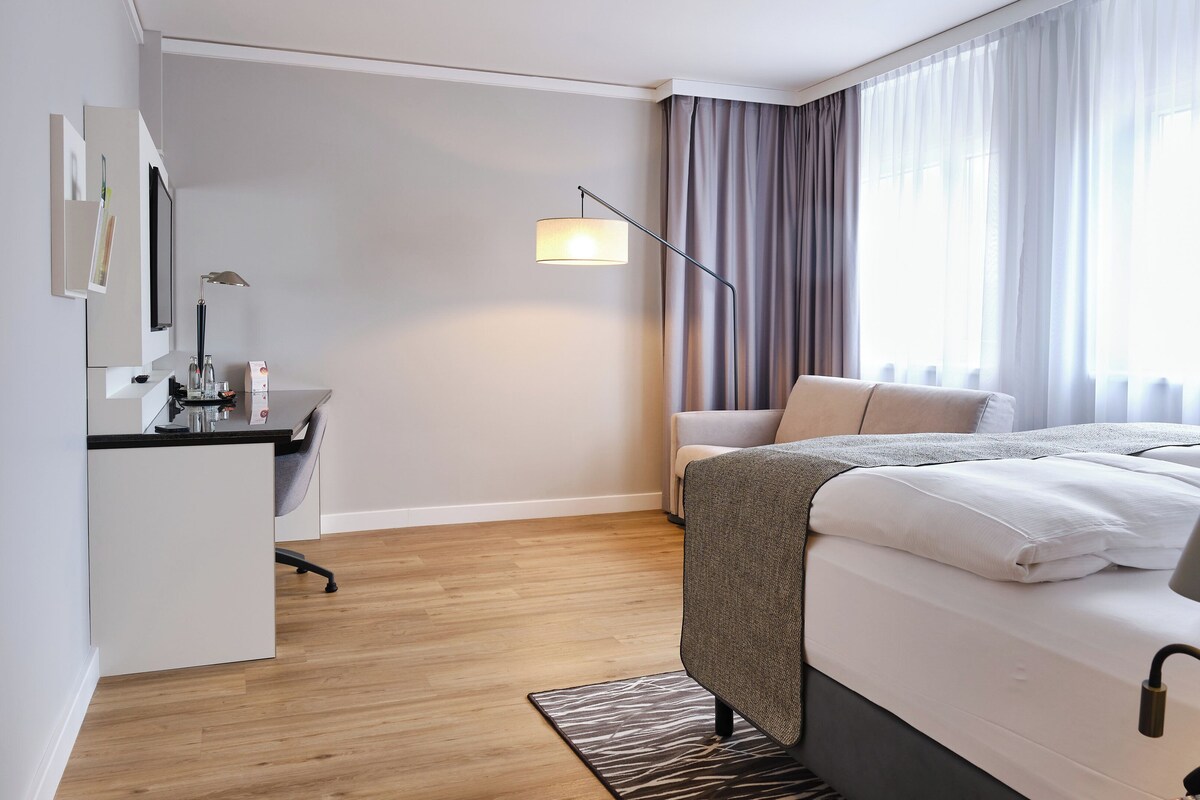 Una moderna camera d'albergo con un letto, una scrivania e una sedia.