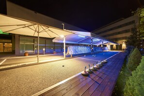 Enjoy a relaxing evening in our outdoor seating area with comfortable chairs and a shaded spot under a large umbrella.