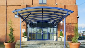 A building entrance with a covered walkway, steps, and potted plants. - Holiday Inn Express Birmingham - Castle Bromwich by IHG (Birmingham)