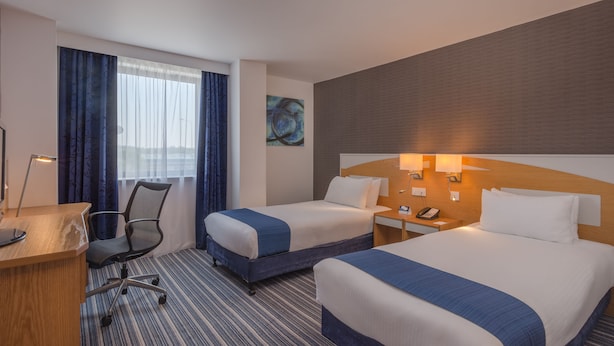 A hotel room with two beds, a desk, a chair, and a large window with curtains. - Holiday Inn Express Birmingham - Castle Bromwich by IHG (Birmingham)