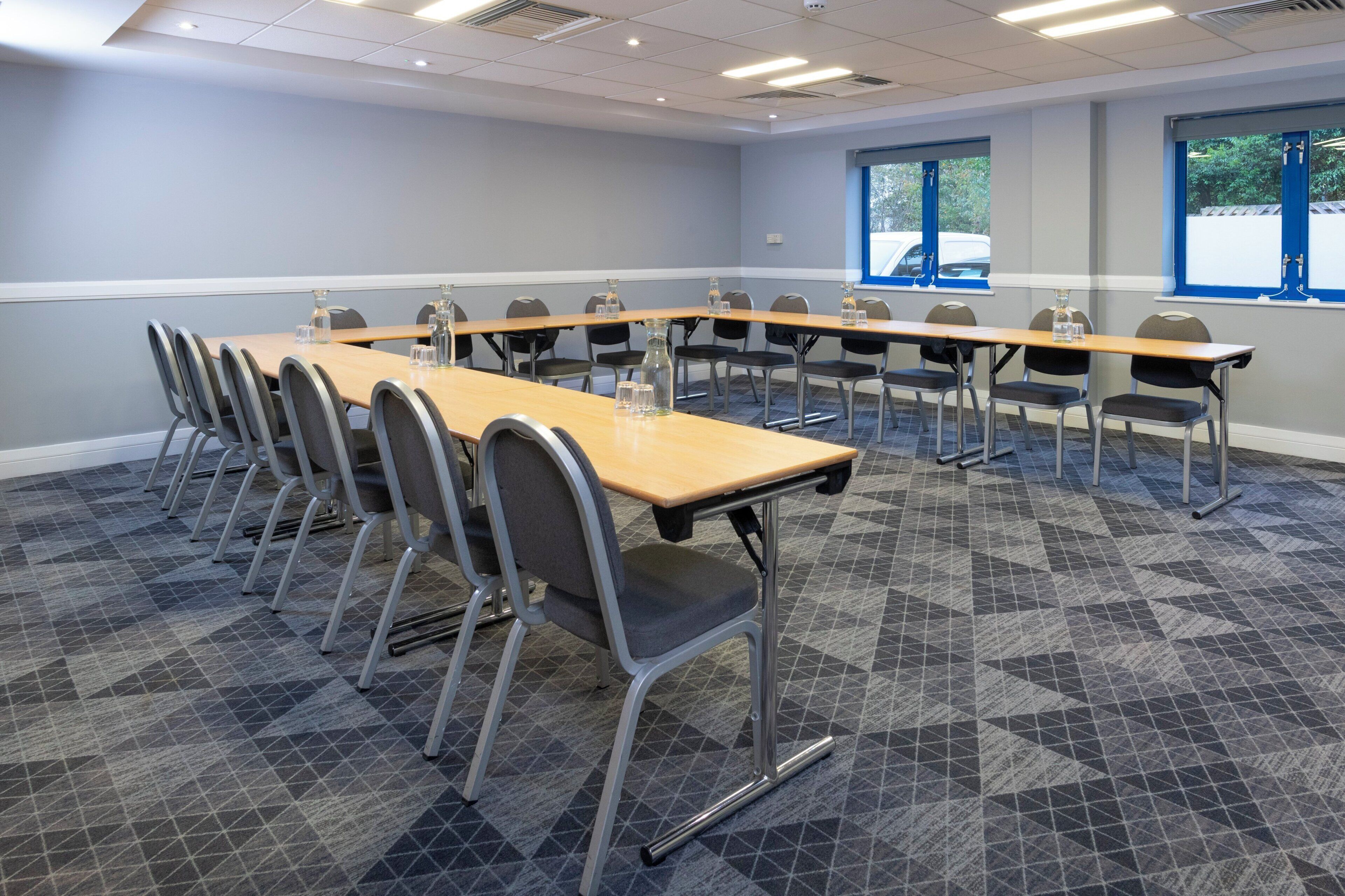 Une salle de conférence avec une longue table, de nombreuses chaises et un sol recouvert de moquette.