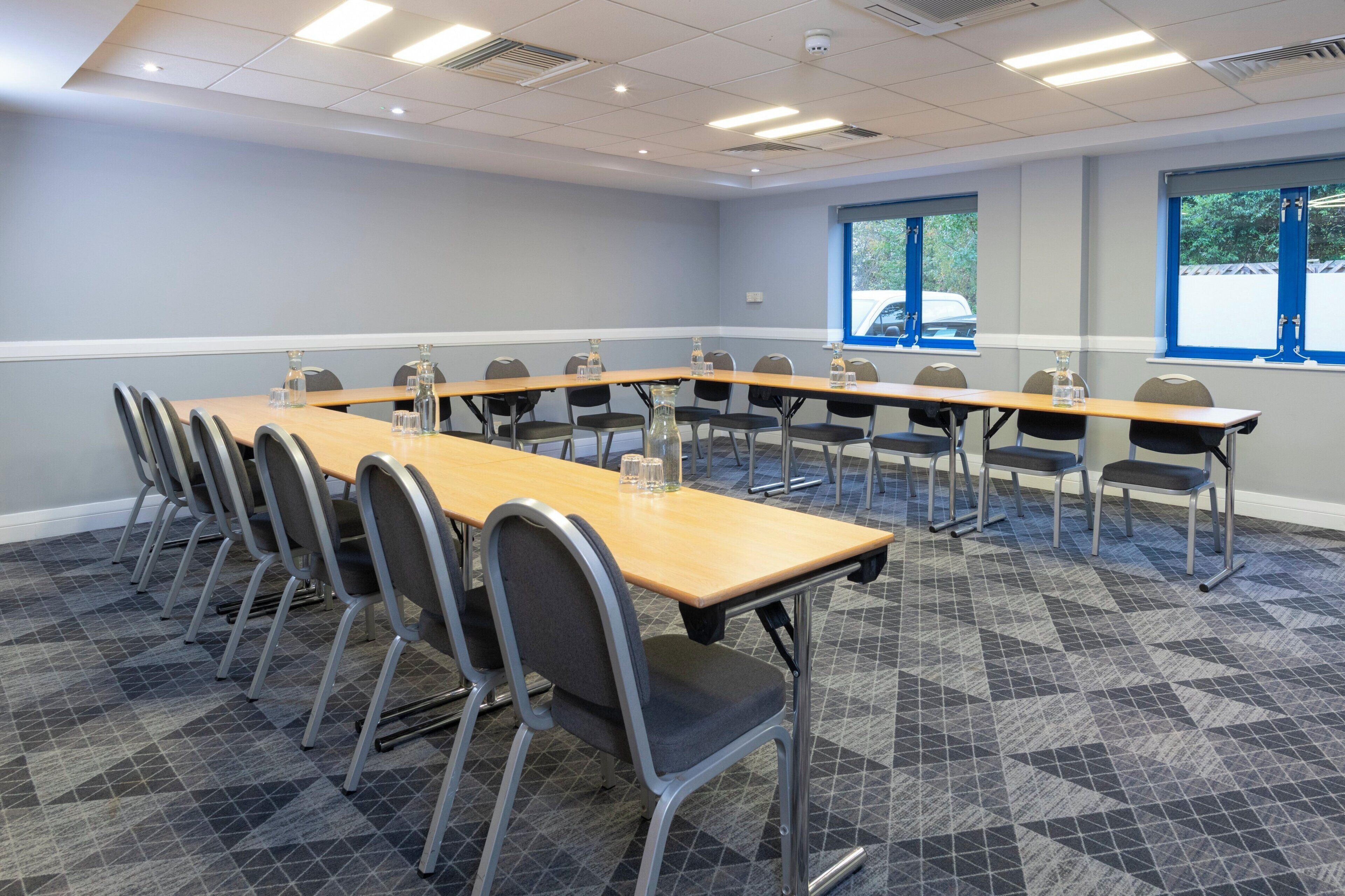 A conference room with a long table, chairs, and windows.