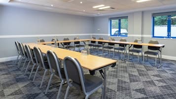 A conference room with a long table, chairs, and windows.