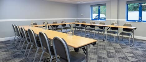 Un salón de conferencias con una larga mesa, sillas y ventanas.