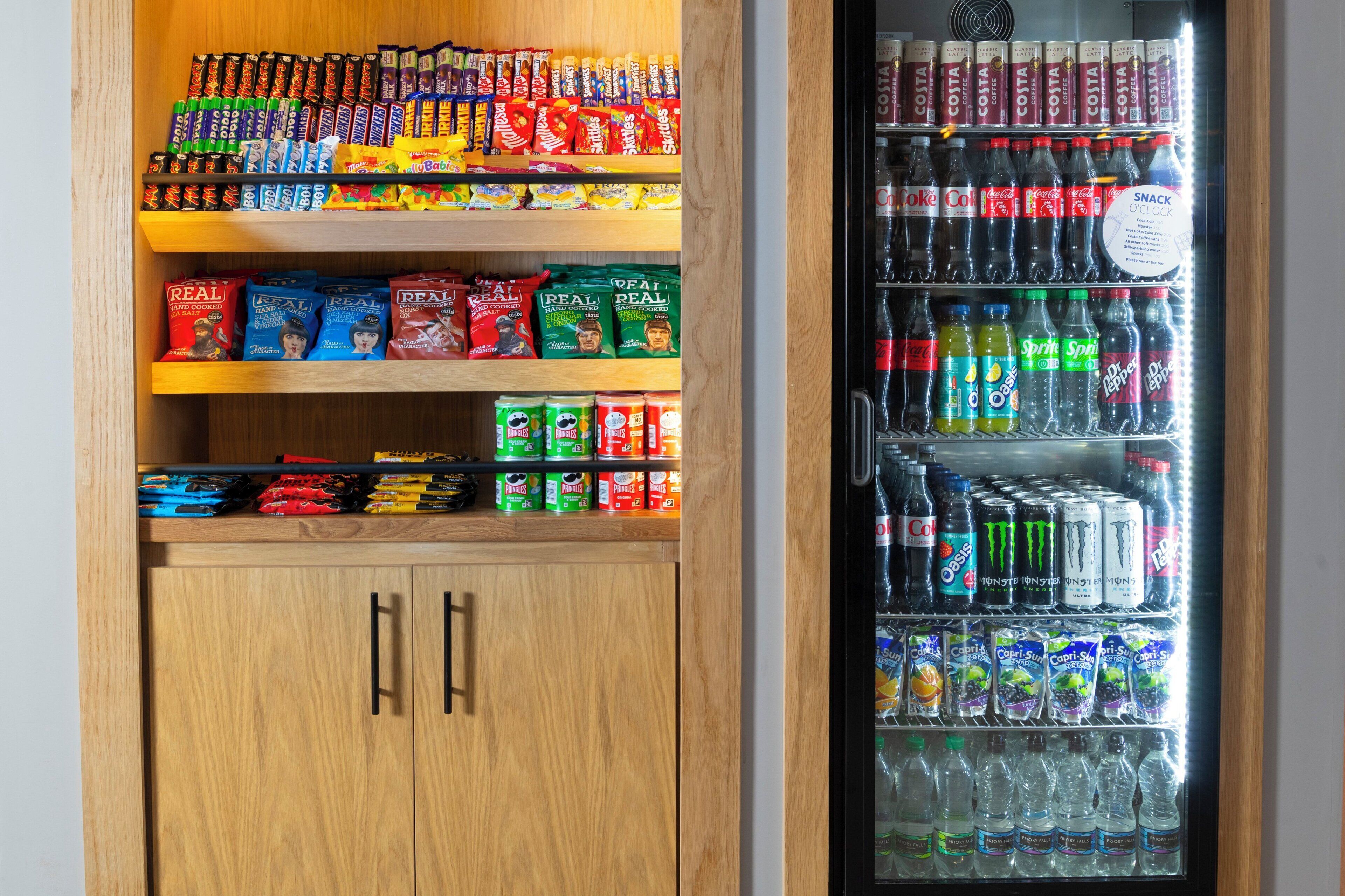 A vending machine stocked with snacks and drinks, including Coca-Cola, Sprite, and various other beverages.